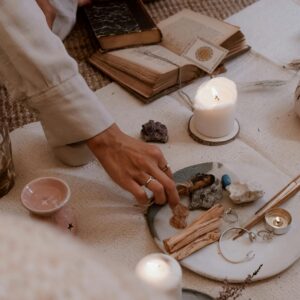 A peaceful ritual scene with candles, crystals, and incense sticks on a wooden table.