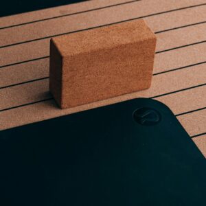 Close-up of a cork yoga block and striped yoga mat, essential for fitness routines.